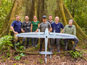 Das Team von Wilderness International mit einer Drohne vor einem großen Urwaldbaum.